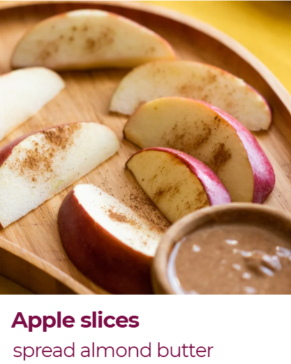 Sliced apples on a wooden tray with almond butter in a small bowl.