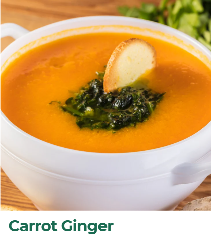 A bowl of carrot ginger soup with a bread slice and chopped greens on top.