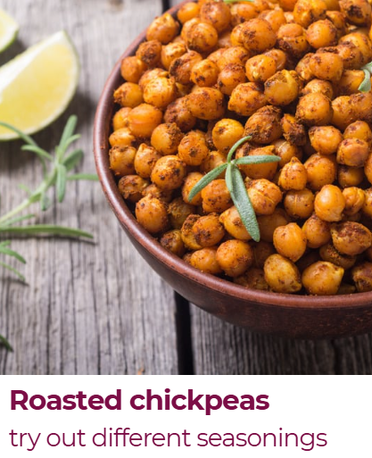 A bowl of roasted chickpeas garnished with a sprig of rosemary, with lemon wedges and fresh rosemary on a rustic wooden surface.
