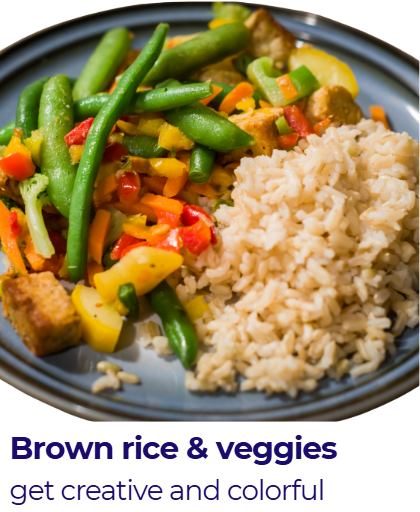 A plate of brown rice with mixed colorful vegetables including green beans, red and yellow bell peppers, and possibly carrots, served on a dark blue plate.
