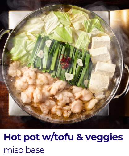 A hot pot filled with tofu, cabbage, green onions, garlic, and other vegetables in a miso-based broth.