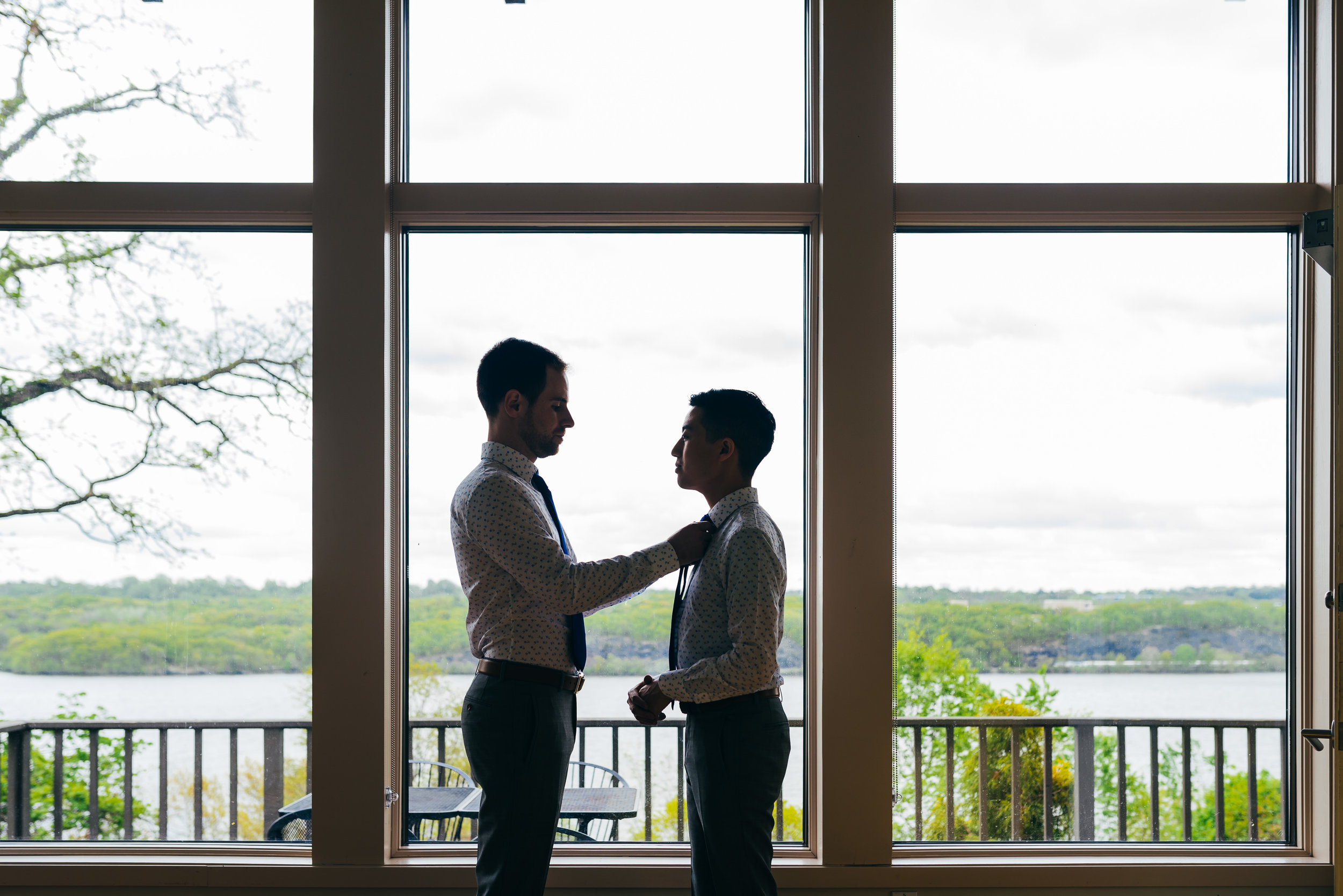 while many couples choose to get ready apart from one another, Chad and Eddie decided to get ready for their wedding together, forgoeing the traditional first look. In this photo, Chad is fixing Eddie's tie as they get ready in matching outfits.