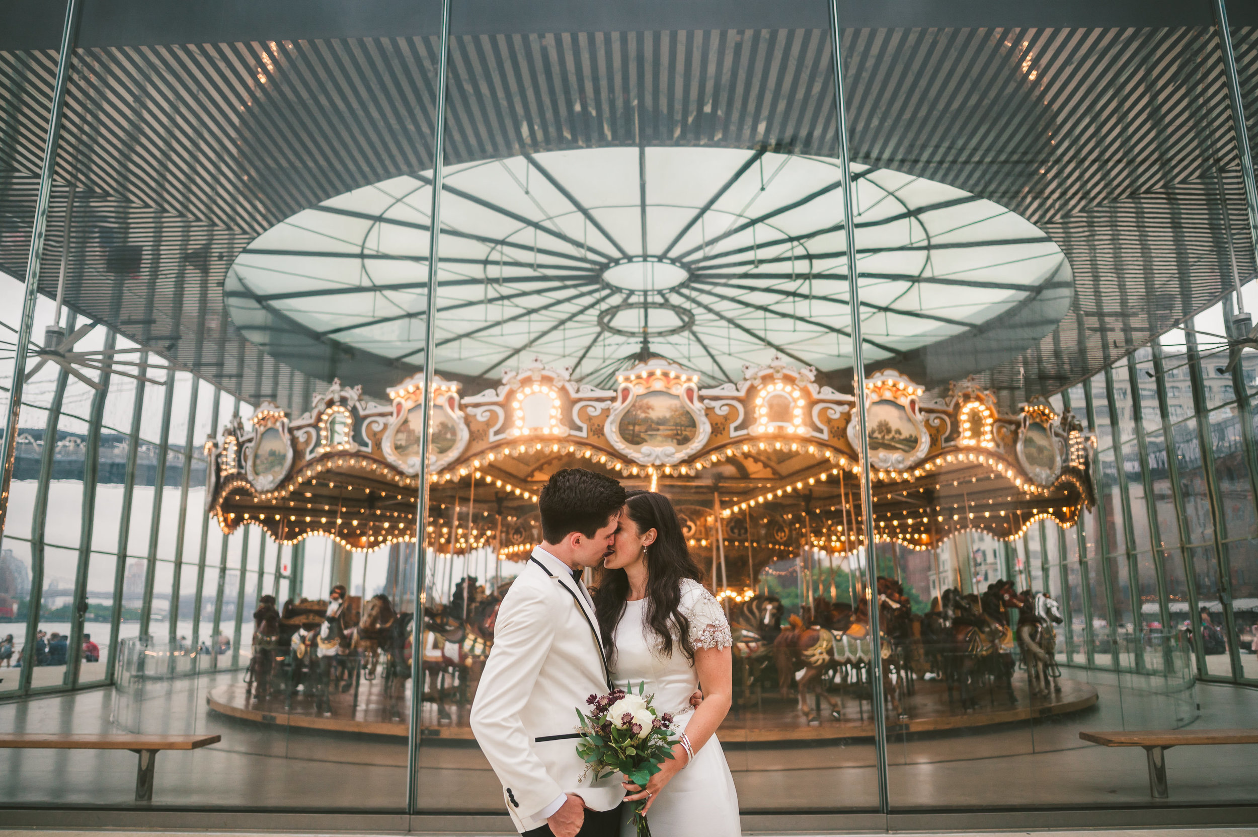 Bride and groom kissing at Jane's Carousel in DUMBO, New York for their destination elopmenet in NYC