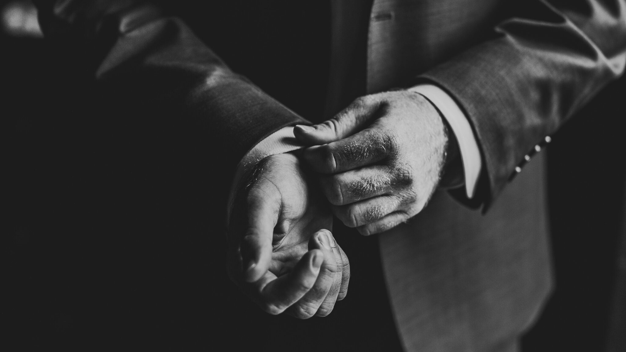 Groom fixing his cufflinks as he gets ready for his wedding in Long Island, New York