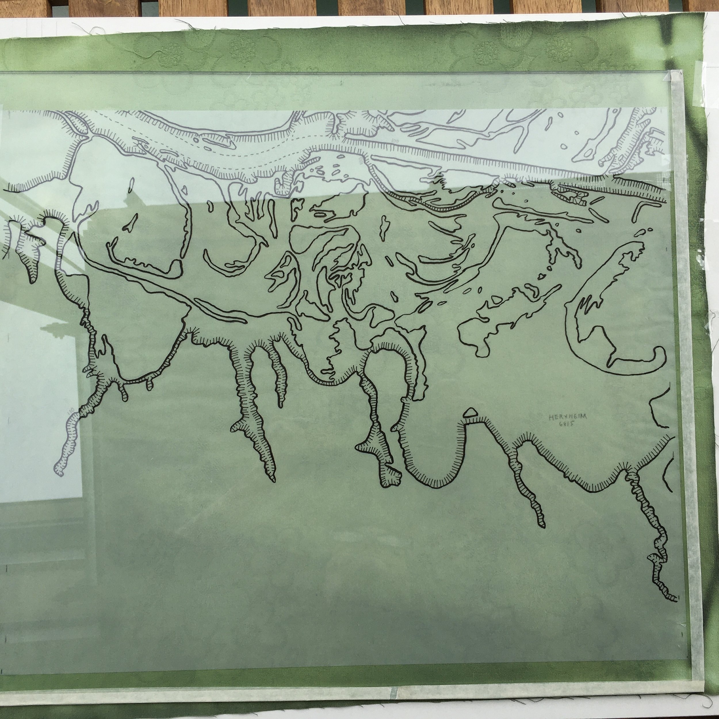 The fabric is placed on a board, the drawing on trace paper on top, then a sheet of glass. The edges are taped to protect my fingers, creating white borders.