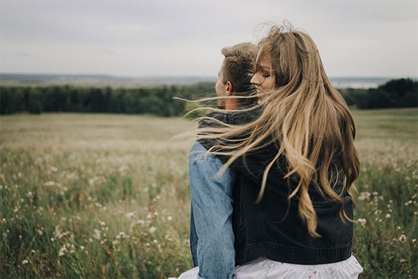 Woman on her partner's back, with her hair blowing in the wind, represents how working with a trauma specialist can help you move forward.