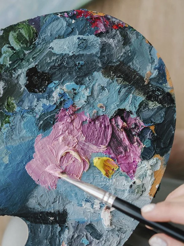 Close-up of a person holding a palette and a paintbrush, represents our art therapy processing group in Los Angeles, CA.
