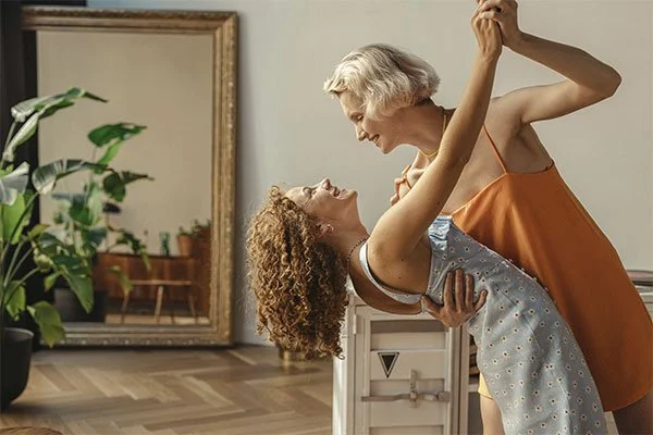 Happy women dancing together in their living room, represents how anxiety therapy in Los Angeles can help you find balance in your life.