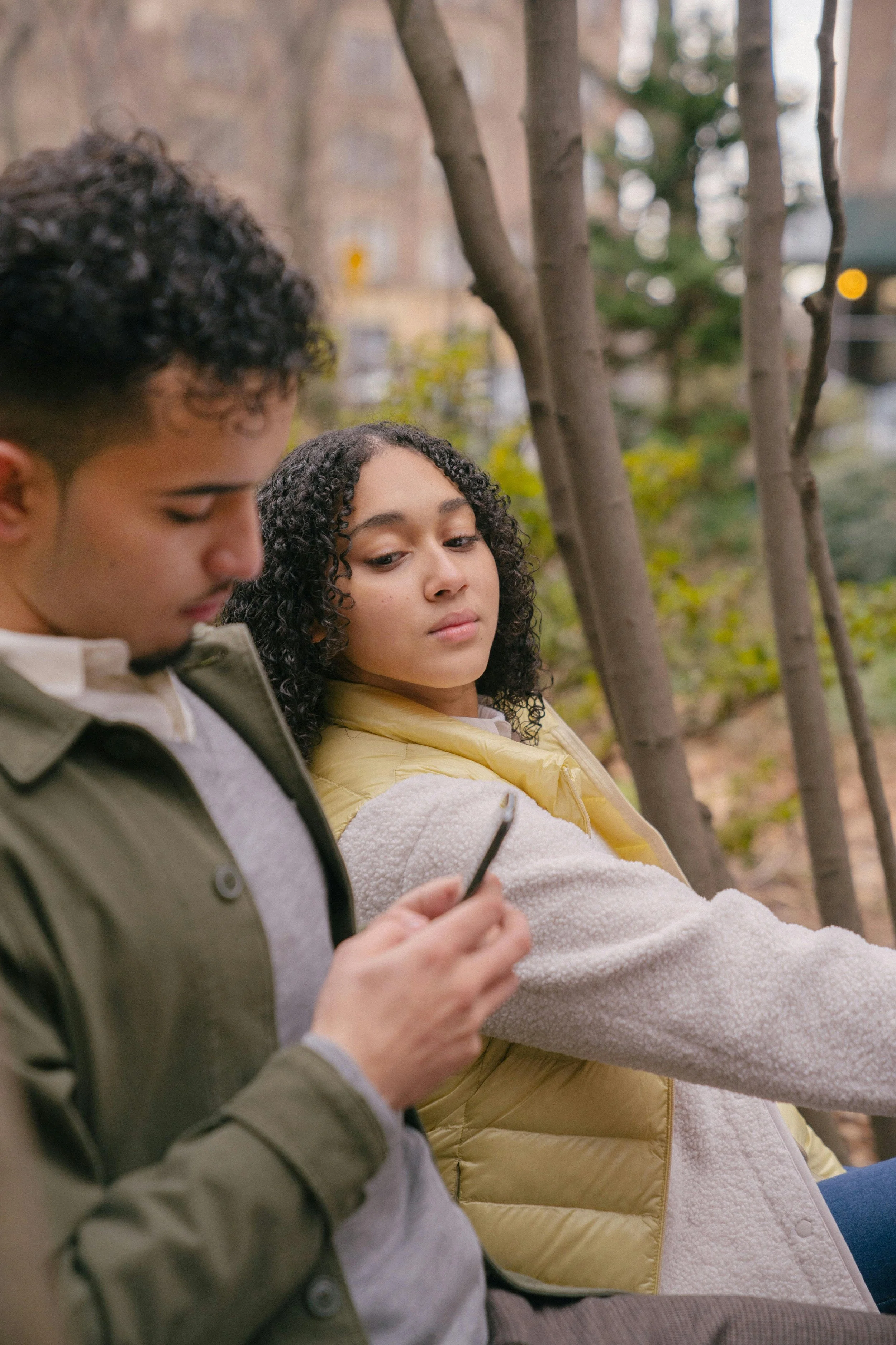 Young couple sitting close outdoors with woman appearing distant, illustrating emotional challenges in relationships with ROCD