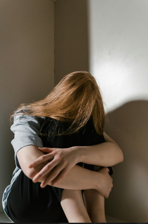 A woman sitting alone in a corner hugging her knees, representing the quiet and hidden struggle of depression in women