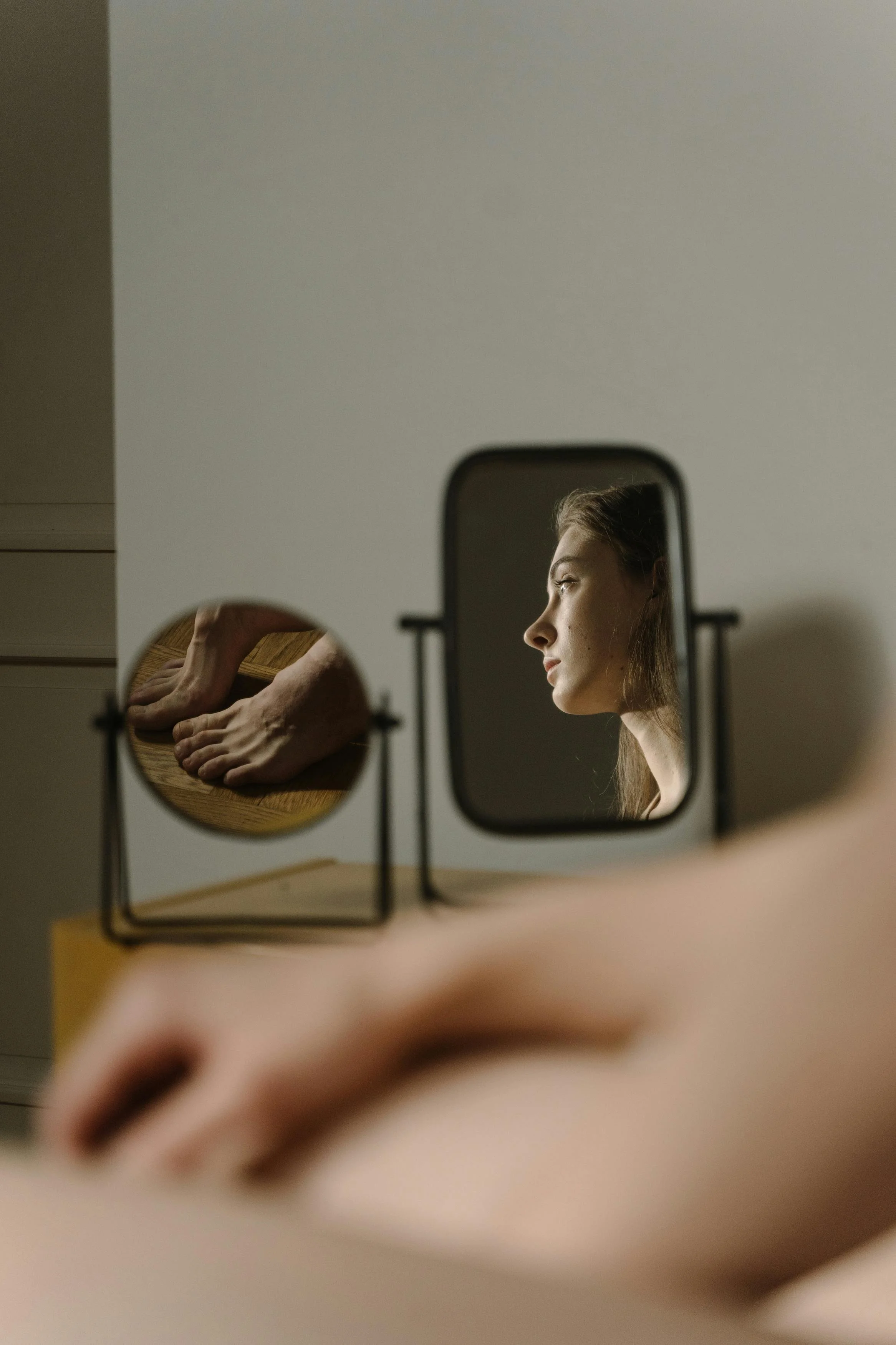Woman reflected in a small mirror looking inward, representing self-doubt and identity loss from narcissistic abuse