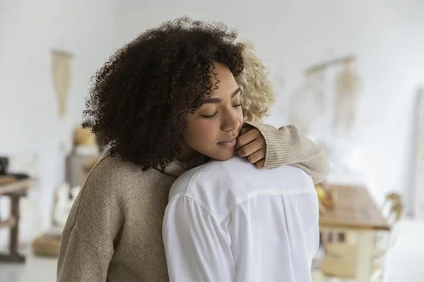 Woman hugging someone in a comforting way, represents how you can find support to deal with grief and loss.