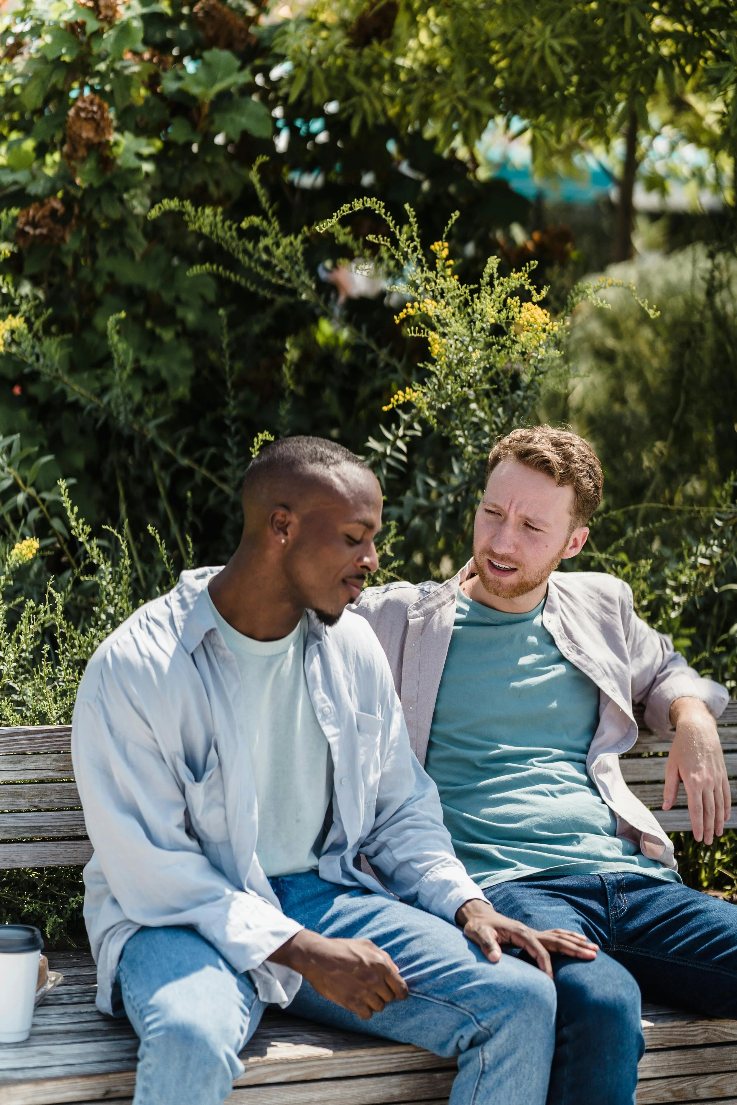 Two men sitting on a park bench having an honest conversation about emotional struggles