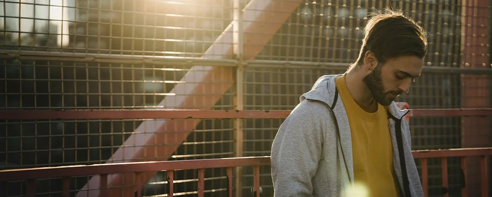 Young man outdoors, lost in thought, represents how an IFS therapist in Los Angeles can help you find balance within yourself.
