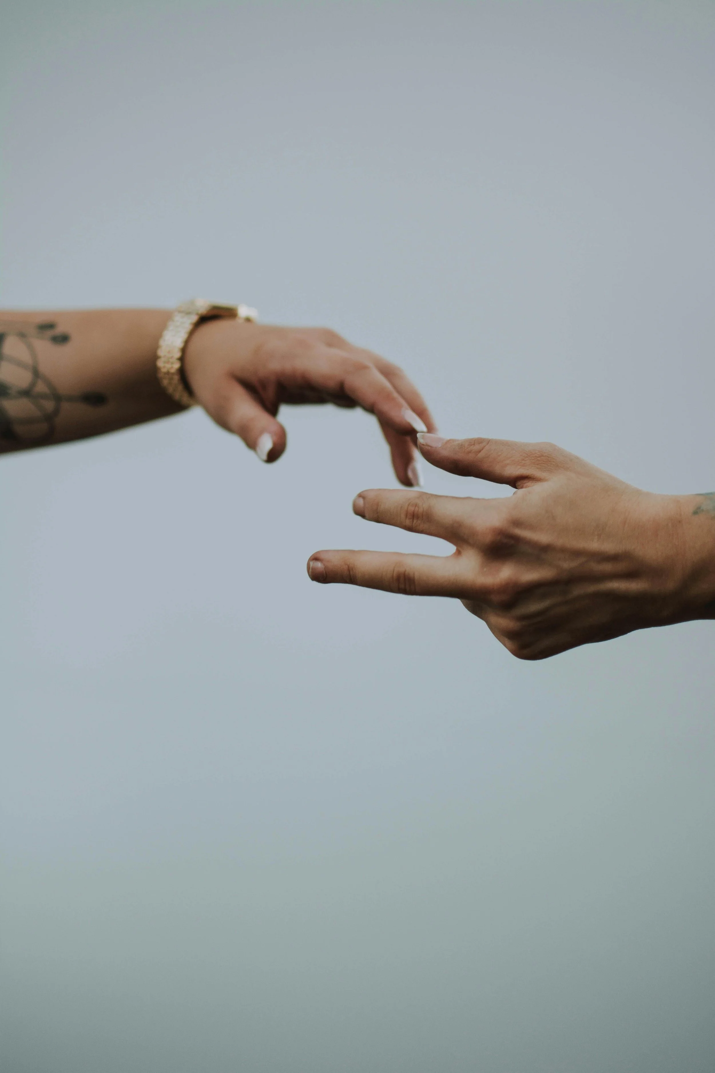 Two hands reaching toward each other against a light background, symbolizing connection and support in relationships