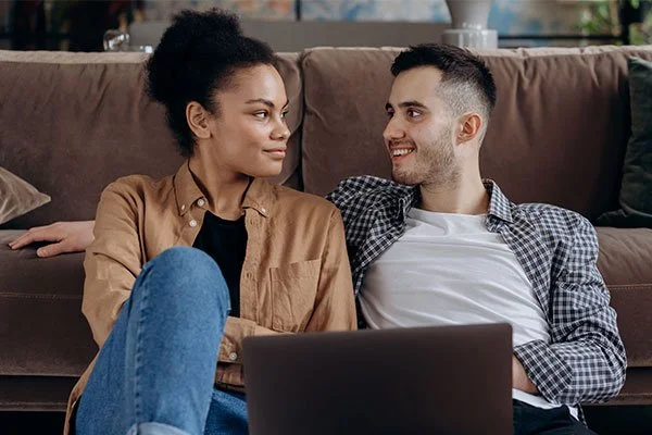 Couple in front of a laptop looking into each others eyes, during a online couple therapy session.