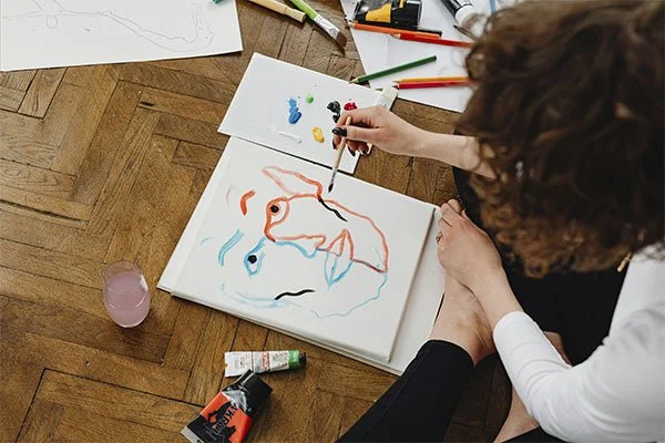 Person drawing a colourful face, represents how art therapy can help you overcome several mental health challenges.