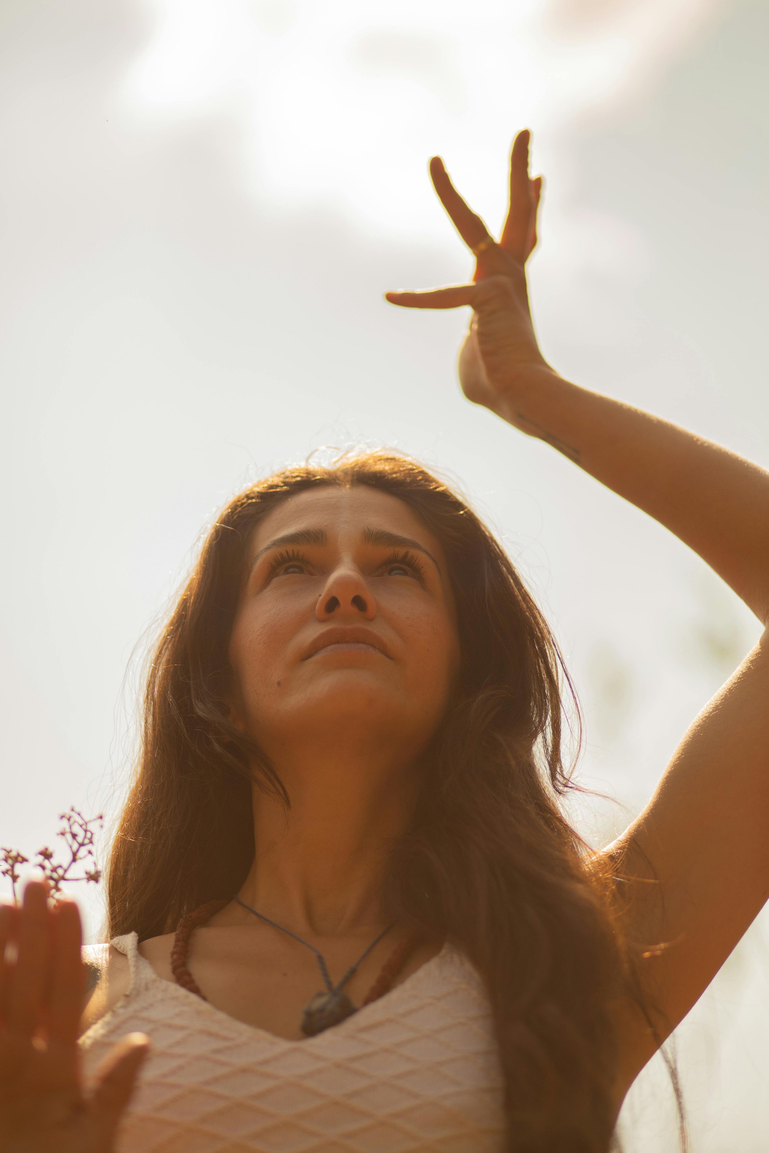 Woman looking up with arms raised in sunlight, representing healing and release from trauma