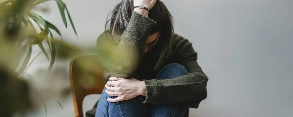 Woman curled up in a chair, represents how depression can feel hopeless but you can find support  through depression therapy in Los Angeles, CA.
