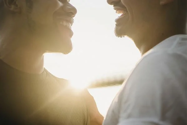 Male couple smiling at sunset, represents how working with a grief and bereavement counselor in Los Angeles can help you move forward.