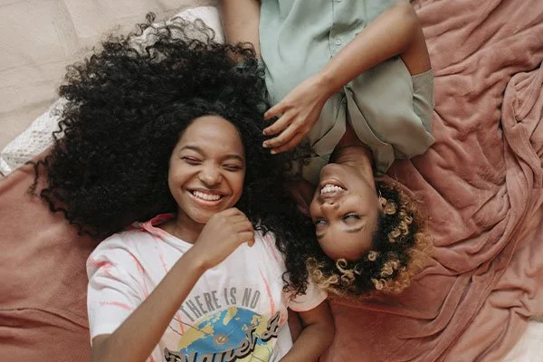 Mother and teenage daughter lying on bed and laughing, represents how working with a teenage therapist in Los Angeles can help you support your teen.