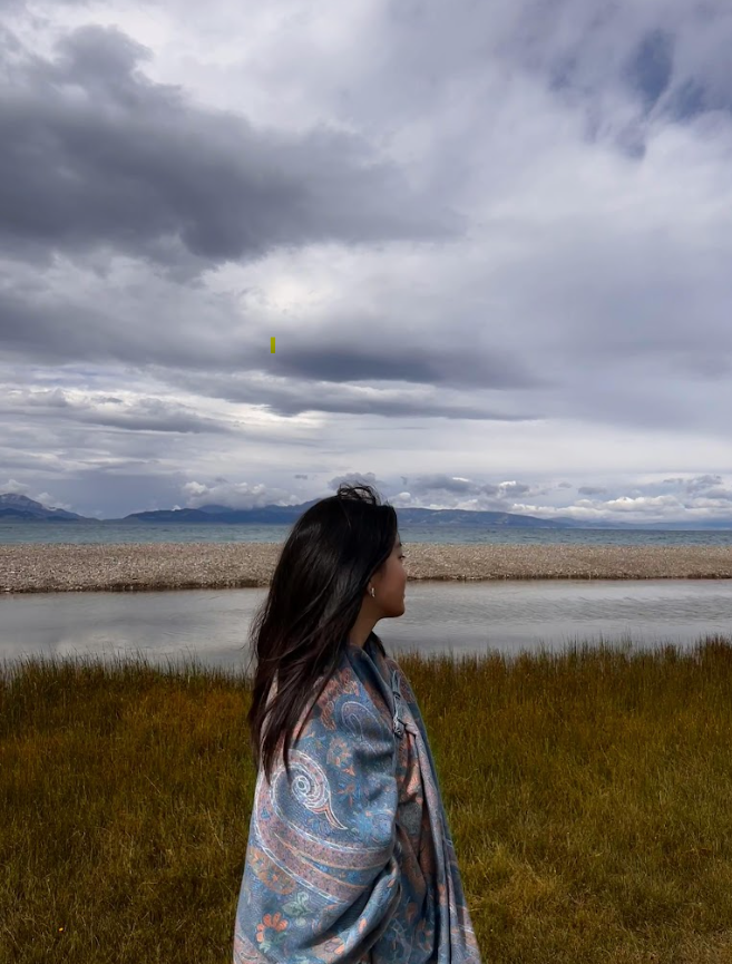 A woman standing by a body of water looking into the distance, reflecting on her emotions and mental health