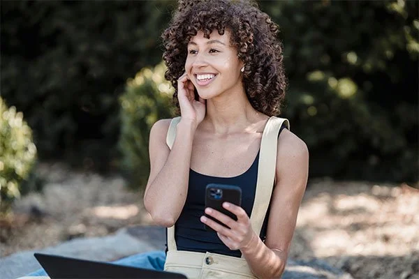 Woman in a park smiling, represents how stress counseling can help you overcome your challenges.