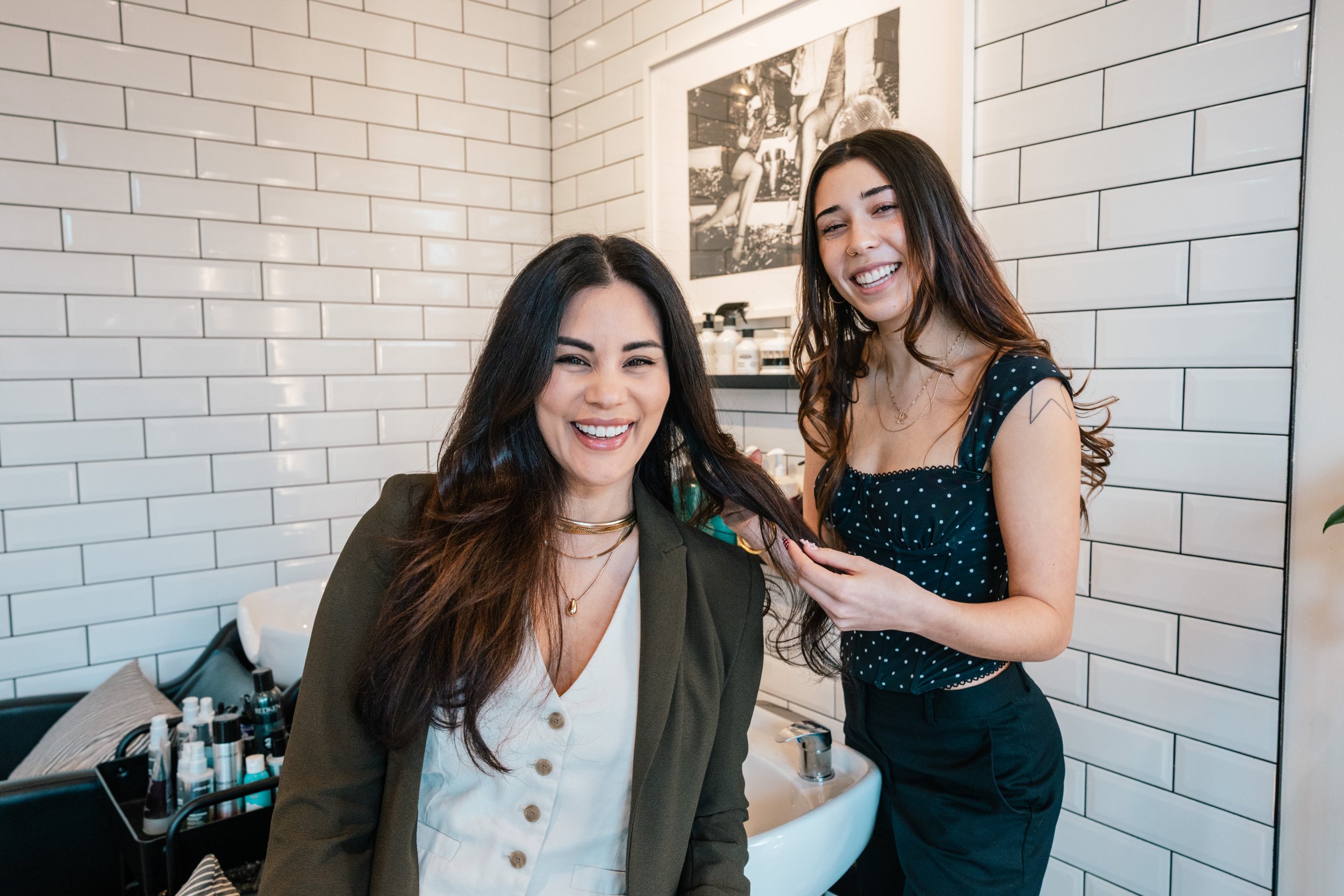 Ambrosia Carey smiling with an independent hairstylist she mentors inside Ivory Salon