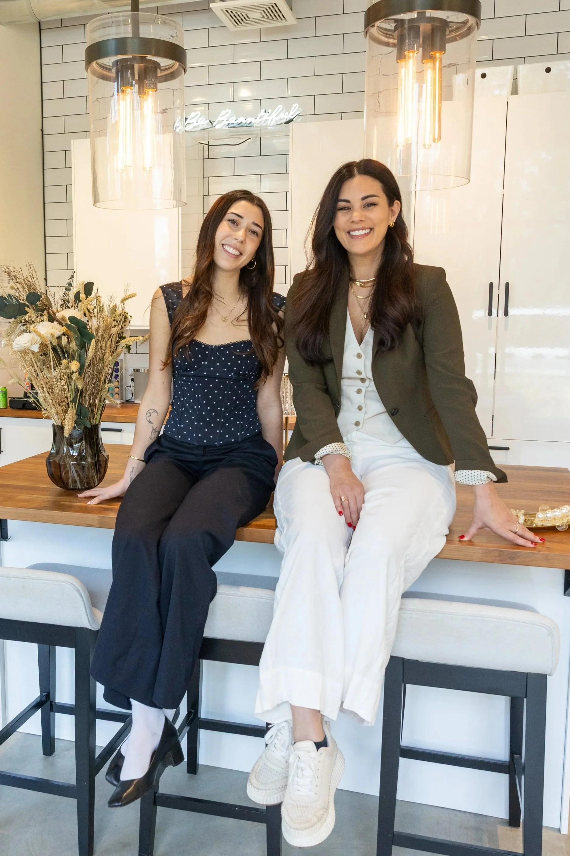Ambrosia Carey seated beside an independent hairstylist she mentors at Ivory Salon
