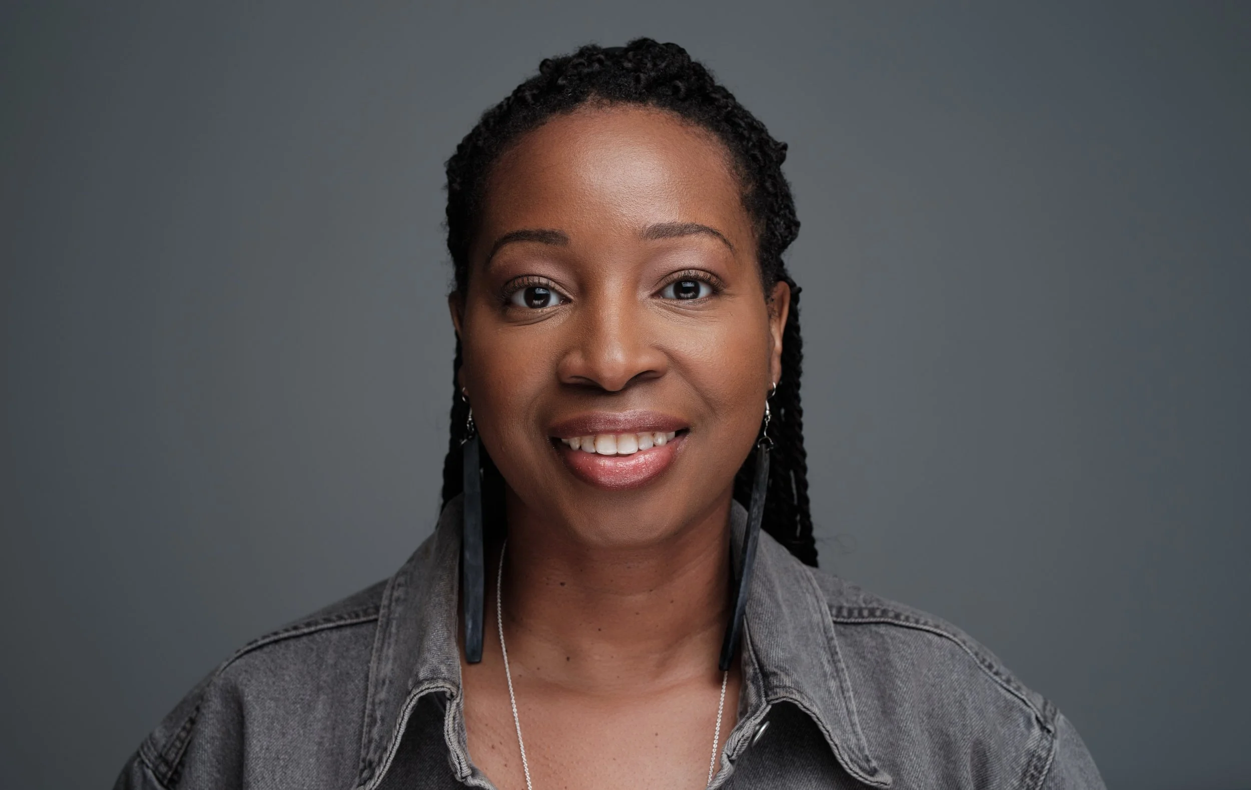 Sakinah Hofler, author, dressed in black denim jacket, smiles