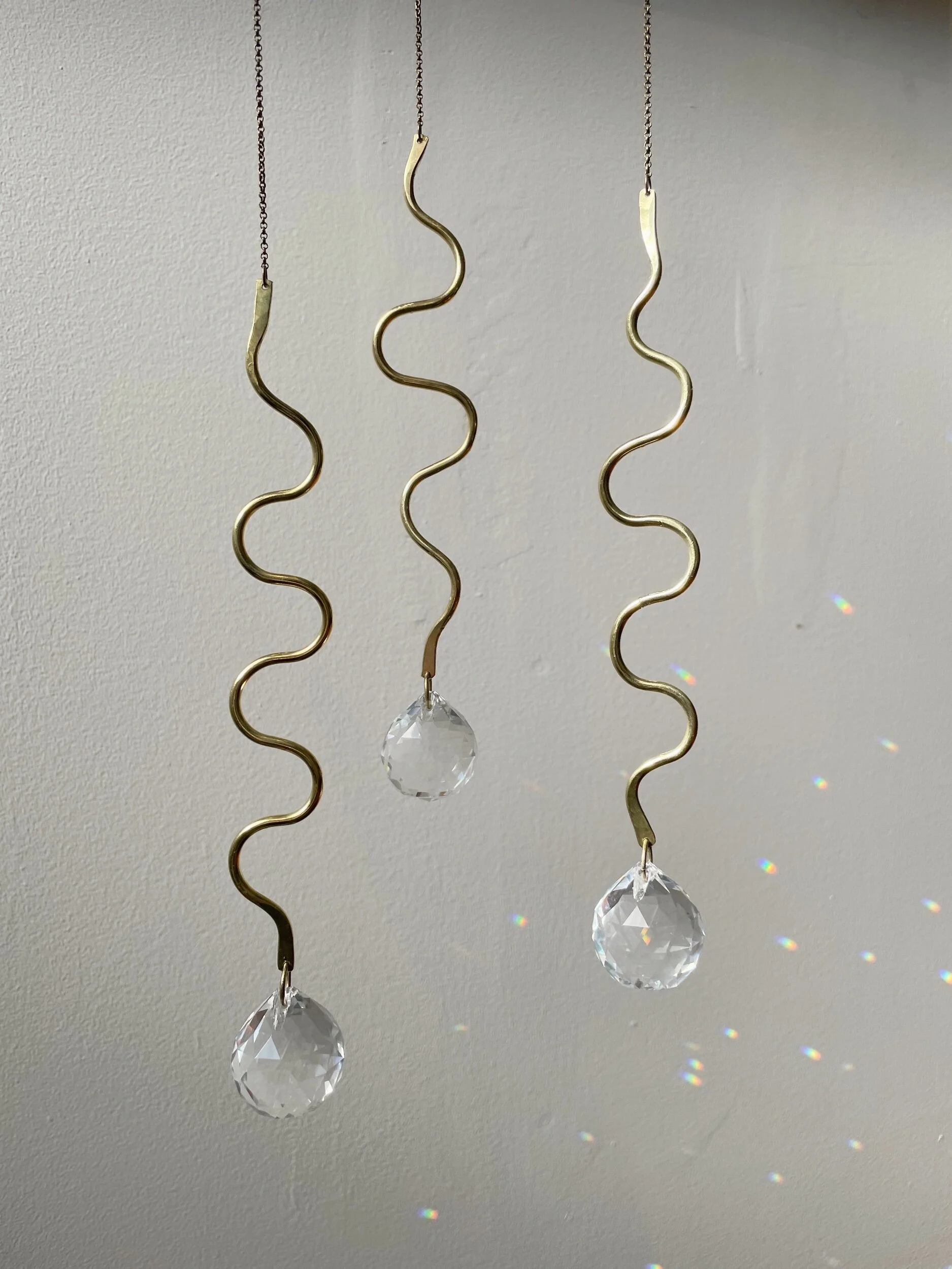 Three brass rod squiggle shape light catchers.