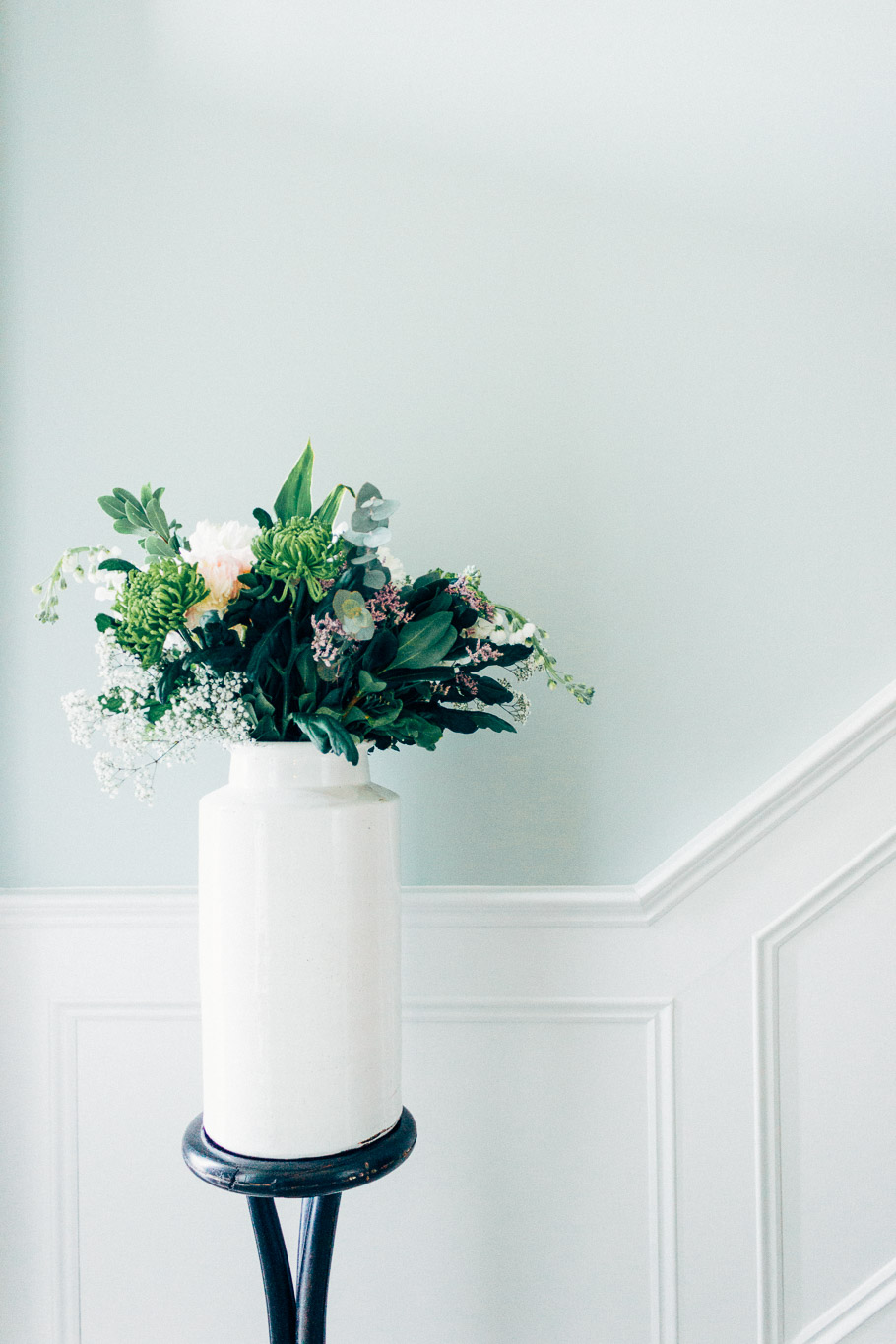 light green and white panelled wall behind bouquet in white vase