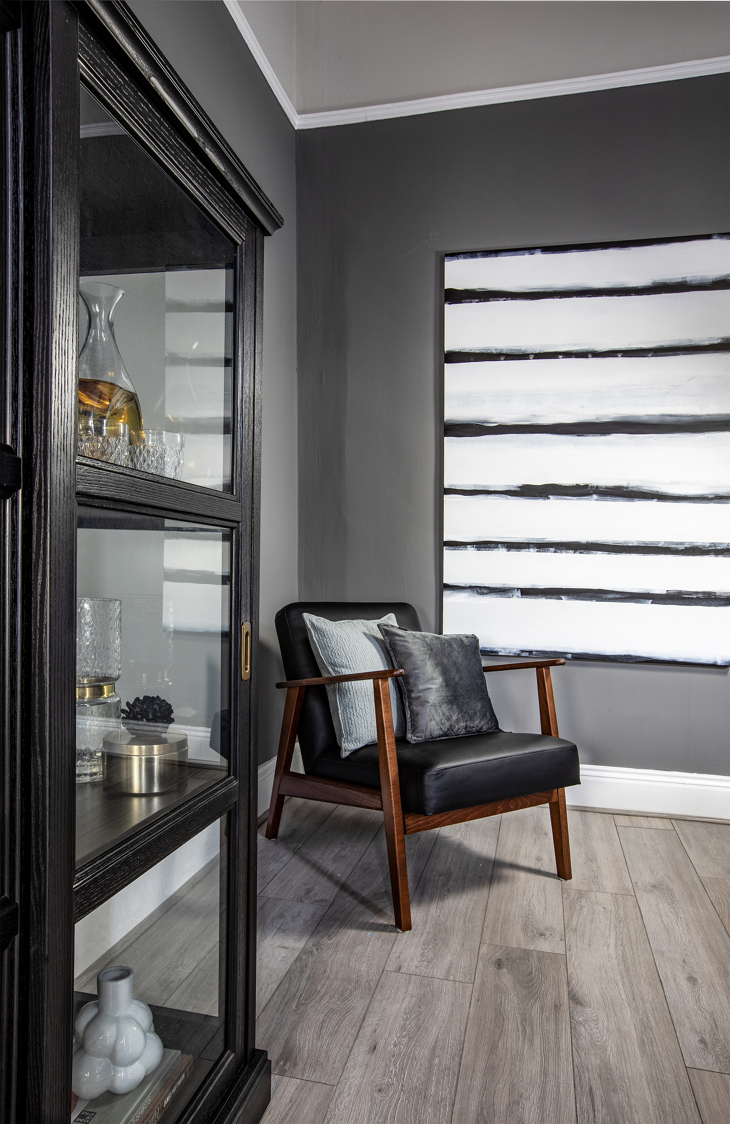 grey wood floors black chair and glass door cabinet