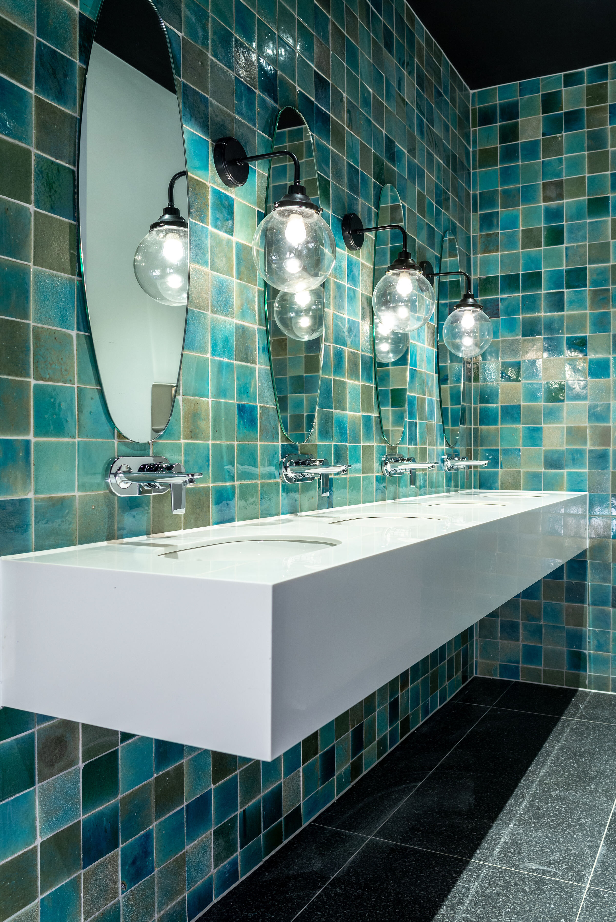 multi-toned green square bathroom tile and floating sink