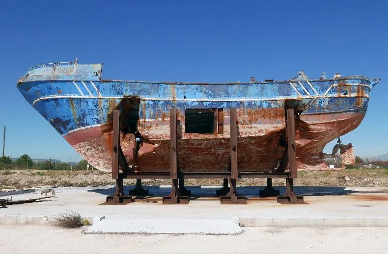 Seen here at the Italian Navy base in Melilli, Sicily, the fishing boat that normally would have accommodated a crew of fifteen but was carrying hundreds of migrants when it was shipwrecked in the Mediterranean on 18 April 2015. Photo © Christoph Büchel/BARCA NOSTRA