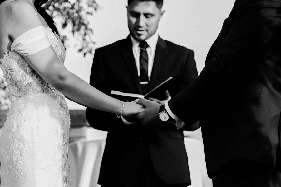 Bride and groom hold hands at wedding ceremony.