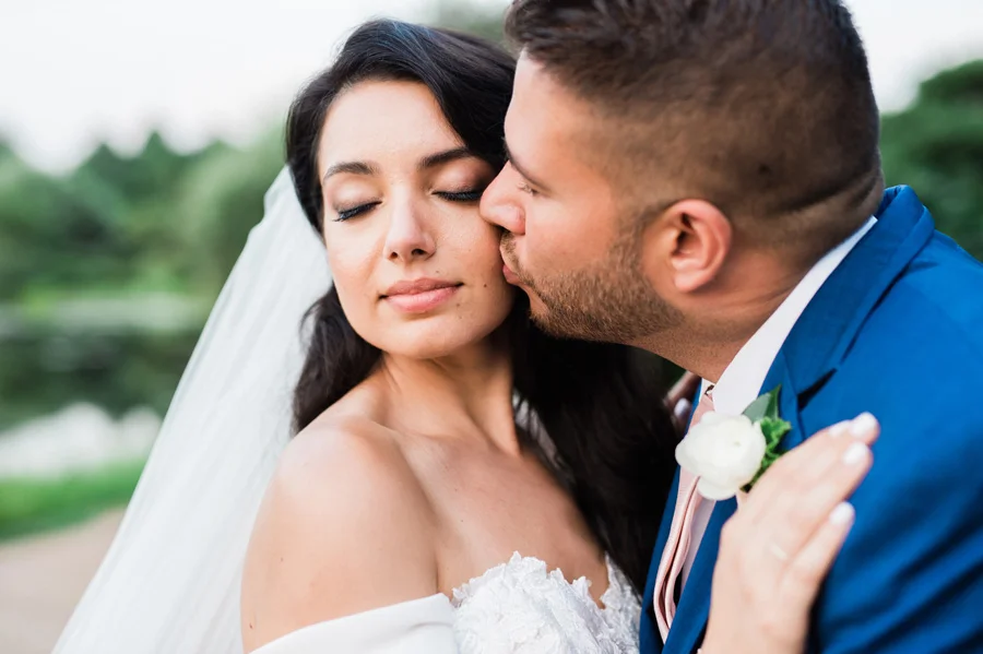Groom kisses bride on cheek.