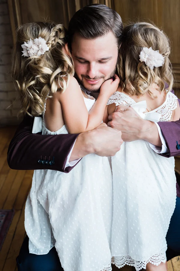 Groom gets a hug from his flower girls.