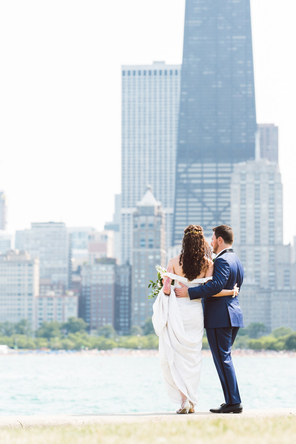 Bride and groom looks at skyline at North Ave Beach, Chicago.