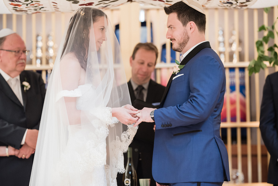 Bride and groom exchage rings at Jewish wedding ceremony.