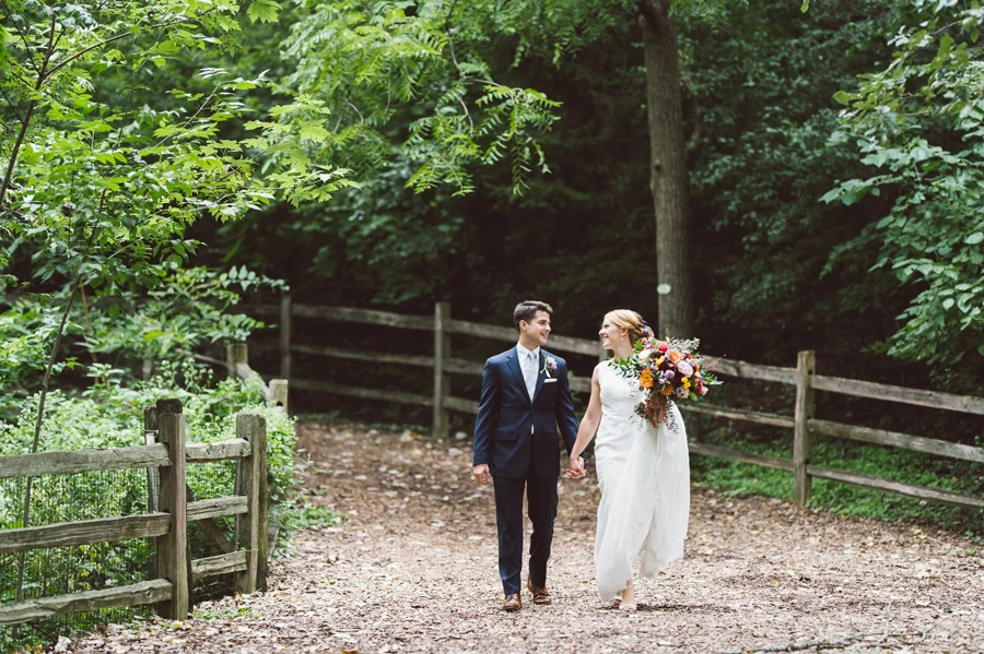 Bride and groom walk along a forest path.