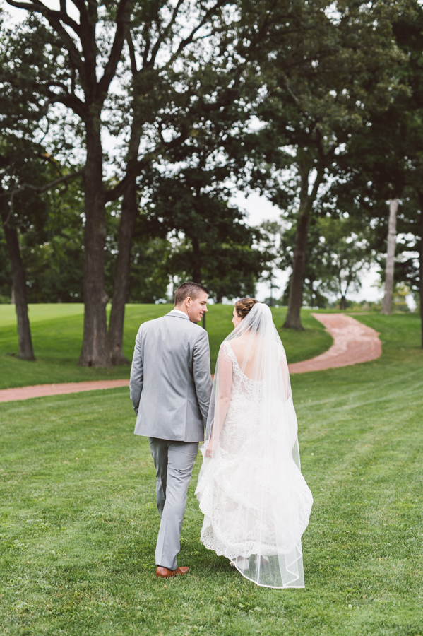 Bride and groom walk together on the golf course.