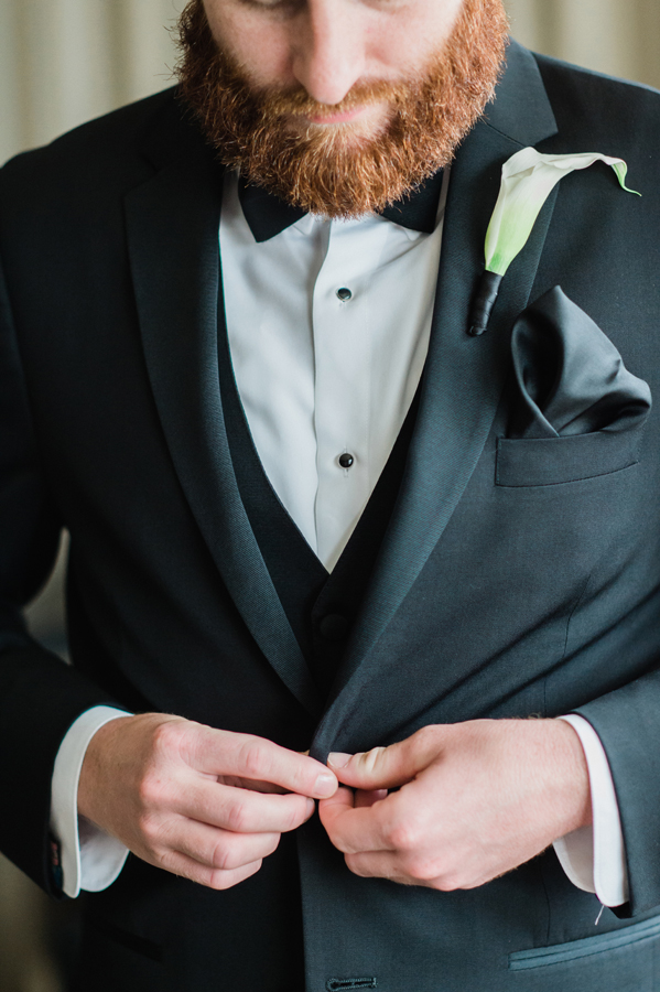 Groom buttons his jacket.