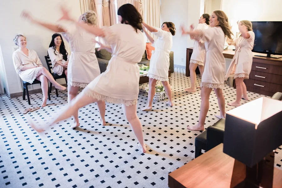 Bridesmaids dance in hotel room.