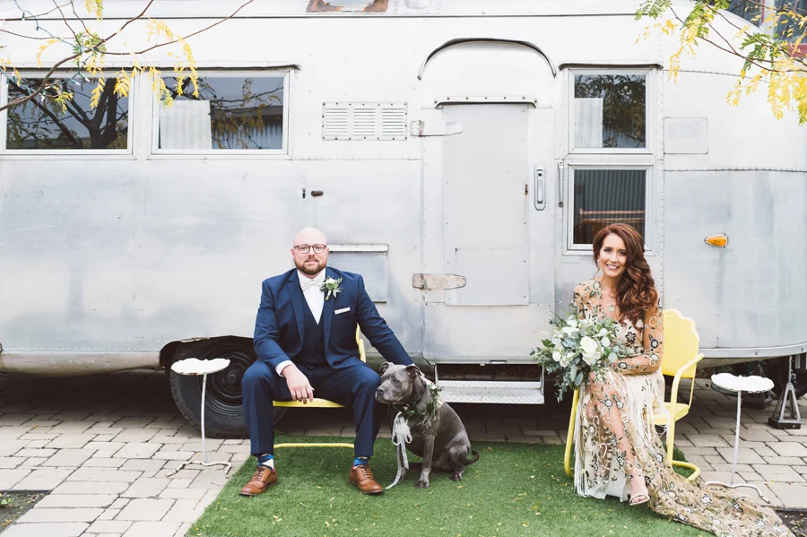 Bride and groom with airstream trailer.