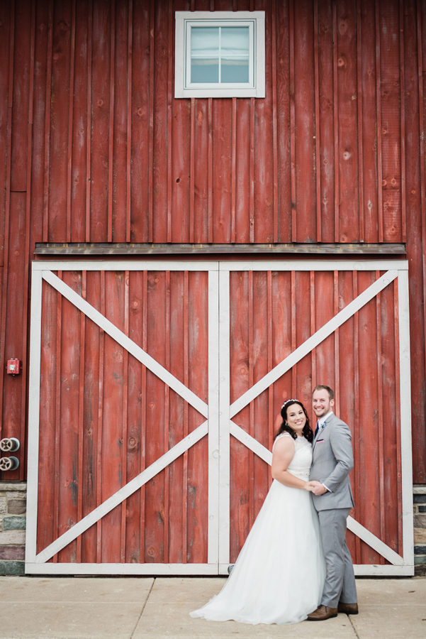 Portrait of bride and groom in front of barn.