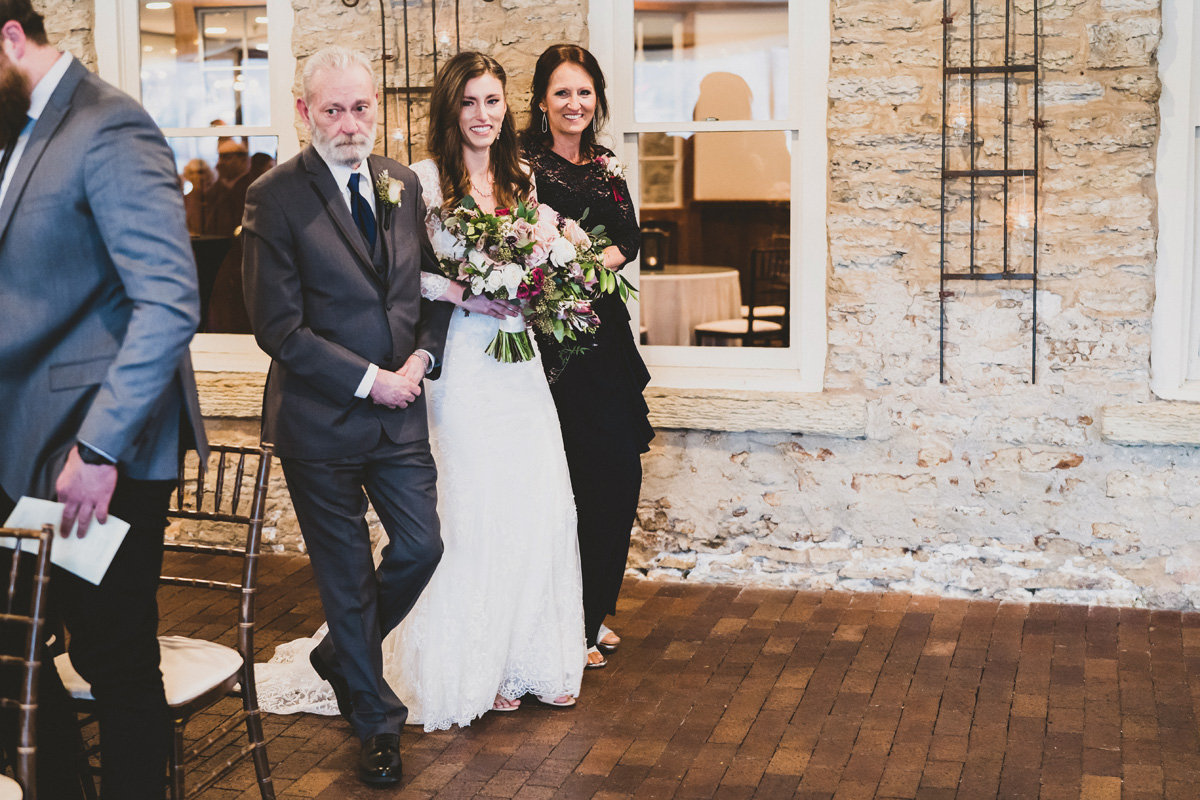 Bride walks in with her parents at ceremony.