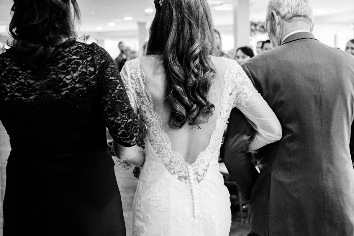 Bride walks in with her parents at ceremony.