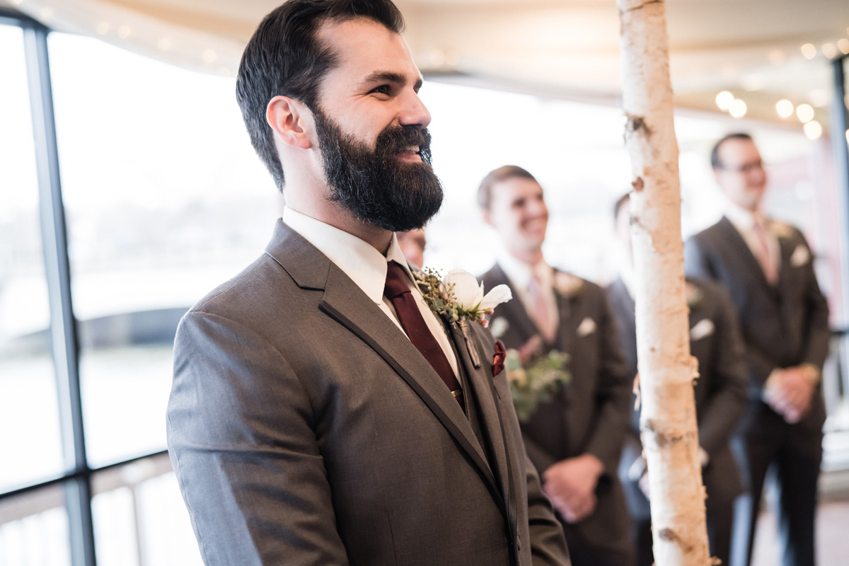 Groom watches his bride walk in during ceremony.