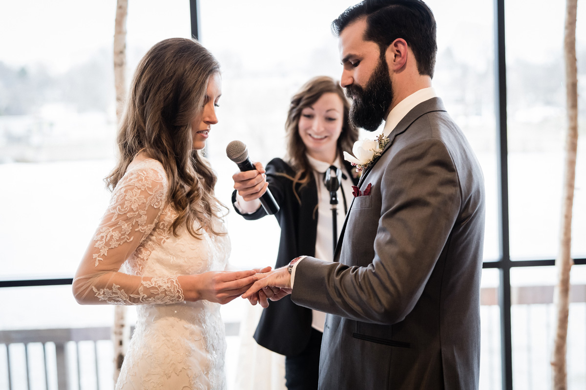 Bride and groom exchange rings during wedding ceremony.